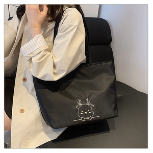 Lifestyle shot of large black canvas tote bag with reindeer print on beige trench coat