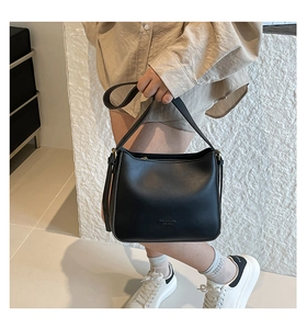 Detail view of the matte black leather handbag featuring gold zipper and fashion embossing