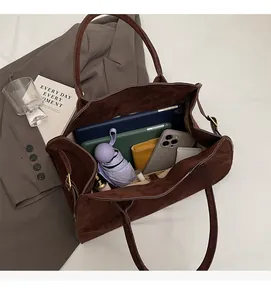 Intérieur spacieux d'un sac cabas en daim marron foncé montrant un ordinateur