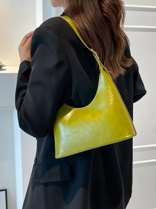 Vintage avocado green faux leather dumpling bag shown on shoulder with black blazer