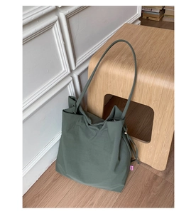 Détail d'un grand sac fourre-tout vert foncé avec texture souple et logo latéral
