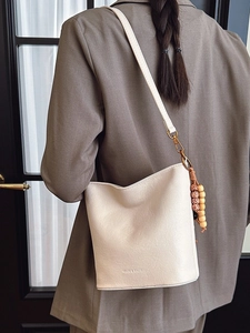 Sac seau en cuir beige avec perles en bois rétro et bandoulière réglable porté par un mannequin