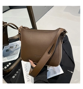 Detailed macro view of dark brown leather crossbody bag with metallic gold logo lettering
