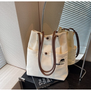 Detail view of canvas tote bag with leather handles and Docile Girl embroidery