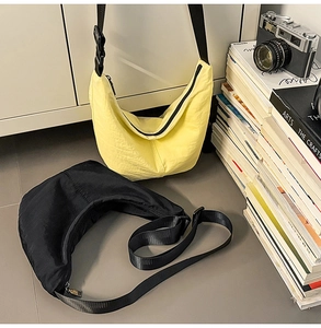 Lightweight crescent crossbody bag showing adjustable strap detail and zipper closure