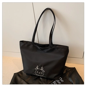 Detail of black nylon tote bag with white cartoon deer embroidery and long shoulder straps
