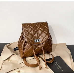 Detail of brown quilted leather backpack with silver clasp on a stylish trench coat