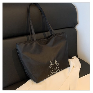 Detailed view of the black canvas tote bag showing the golden elk embroidery and texture