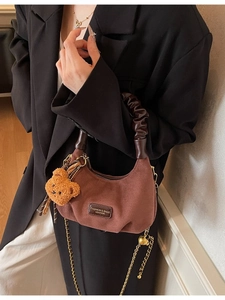 Deep brown crescent suede handbag with stylish gold chain and plush bear charm