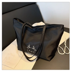 Close-up of black canvas tote bag with white cartoon deer embroidery and dual shoulder straps