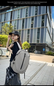 Detail view of a light grey travel backpack with black vertical zippers and side straps