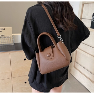 Detailed view of the brown lychee-patterned leather bucket bag worn by a model