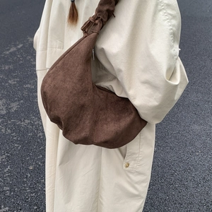 Detail of a large brown suede crescent bag featuring a stylish drawstring shoulder strap