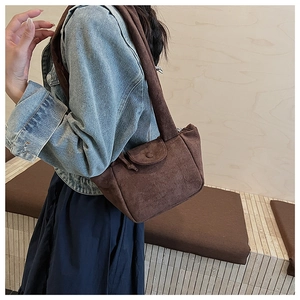 Detail of retro brown suede shoulder bag showing soft texture and front flap pocket