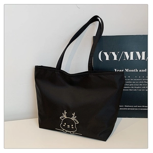 Close-up of black tote bag showing durable nylon fabric and gold deer embroidery detail