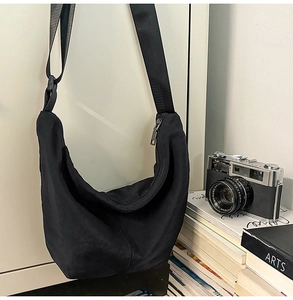 Detail of black nylon crescent bag with adjustable strap and silver metal zipper closure