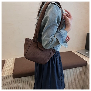 Detail of dark brown matte suede hobo bag with wide shoulder strap on casual outfit