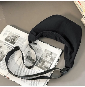 Minimalist black nylon half-moon bag on an open magazine for urban daily commuting