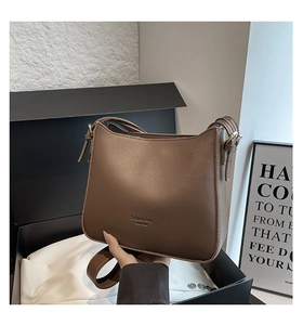 Close-up of brown leather saddle bag with New York gold lettering in a luxury gift box