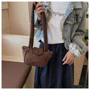 Close-up of a brown suede bucket bag with vintage pleats and a slim shoulder strap