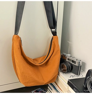 Close-up of caramel orange nylon crescent bag with adjustable wide black shoulder strap