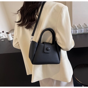 Close-up of black lychee grain leather handbag featuring vintage round buckle and handle
