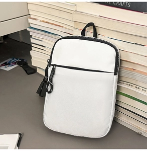 Detailansicht der weißen Brusttasche aus Nylon mit schwarzen Reißverschlüssen und Kordeln