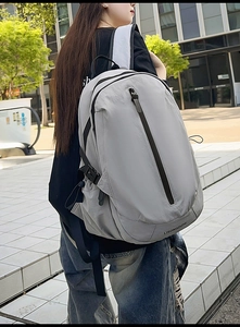 Detail of light grey waterproof nylon travel backpack with front vertical zipper and side pocket