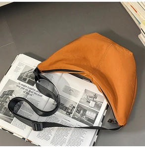 Detail of caramel nylon crescent bag featuring black zipper and adjustable strap
