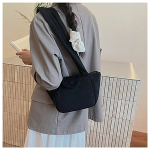 Minimalist black faux suede shoulder bag with pleated detail on a female model