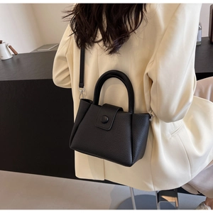 Détail du sac à main noir texture litchi avec boucle ronde et fine bandoulière réglable