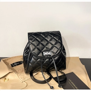 Detail of black quilted leather backpack with twist lock closure on a stylish trench coat