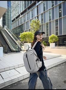 Model wearing a large grey water-resistant travel backpack in an urban city setting
