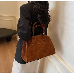 Détail d'un sac cabas en daim marron avec des poignées renforcées et des coutures précises