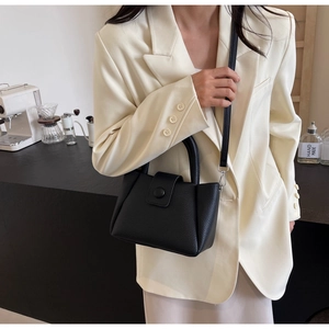 Détail du sac seau noir en cuir grainé litchi avec boucle ronde et bandoulière fine
