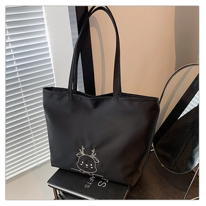 Detail of a large black tote bag featuring a cute white cartoon deer pattern on nylon fabric