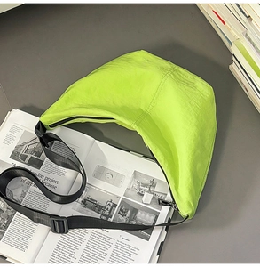 Detailed top view of a neon green nylon crescent bag on an open fashion magazine