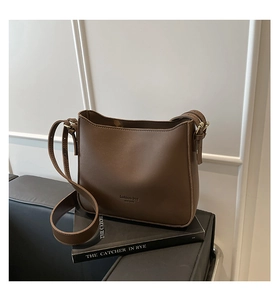 Detail view of brown matte PU leather bucket bag on book with gold hardware buckle