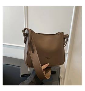 Detail view of brown matte leather crossbody bucket bag with wide shoulder strap