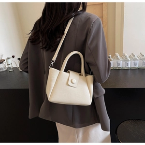 Detail of cream white pebbled leather bucket bag styled with a grey casual blazer