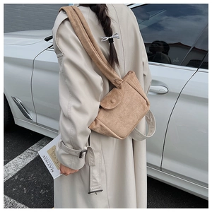 Detail of khaki corduroy bucket bag with pleated texture and wide strap on model