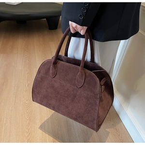 Détail rapproché du sac cabas en daim marron avec poignées solides et coutures fines