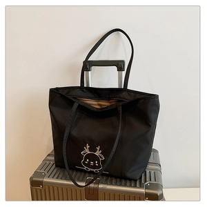 Close-up of black canvas tote bag with deer print placed on a silver suitcase