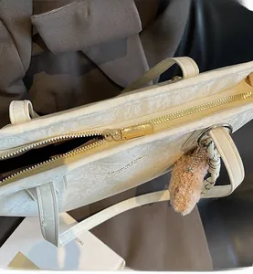 Close-up of smooth golden metal zipper and cream leather texture on tote bag detail