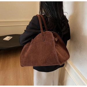 Détail d'un grand sac cabas en daim marron avec boucles de réglage en métal doré sur le côté