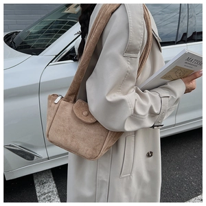 Detail of warm camel suede bucket bag with round buckle pocket and zipper closure