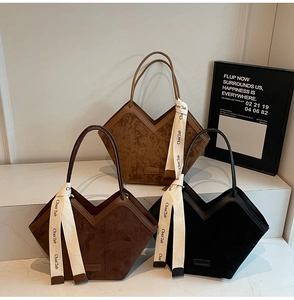 Suede tote bags in camel, brown, and black with decorative ribbons on white stand