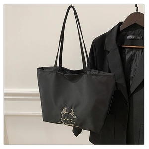 Detail view of black nylon tote bag with golden reindeer embroidery and slim straps