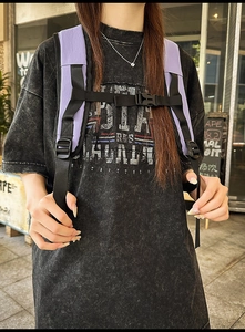 Detail of purple backpack chest buckle and black adjustable shoulder straps on gray shirt