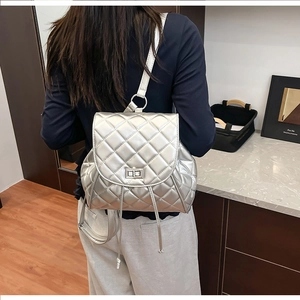 Silver quilted backpack with metallic finish and metal lock shown on person